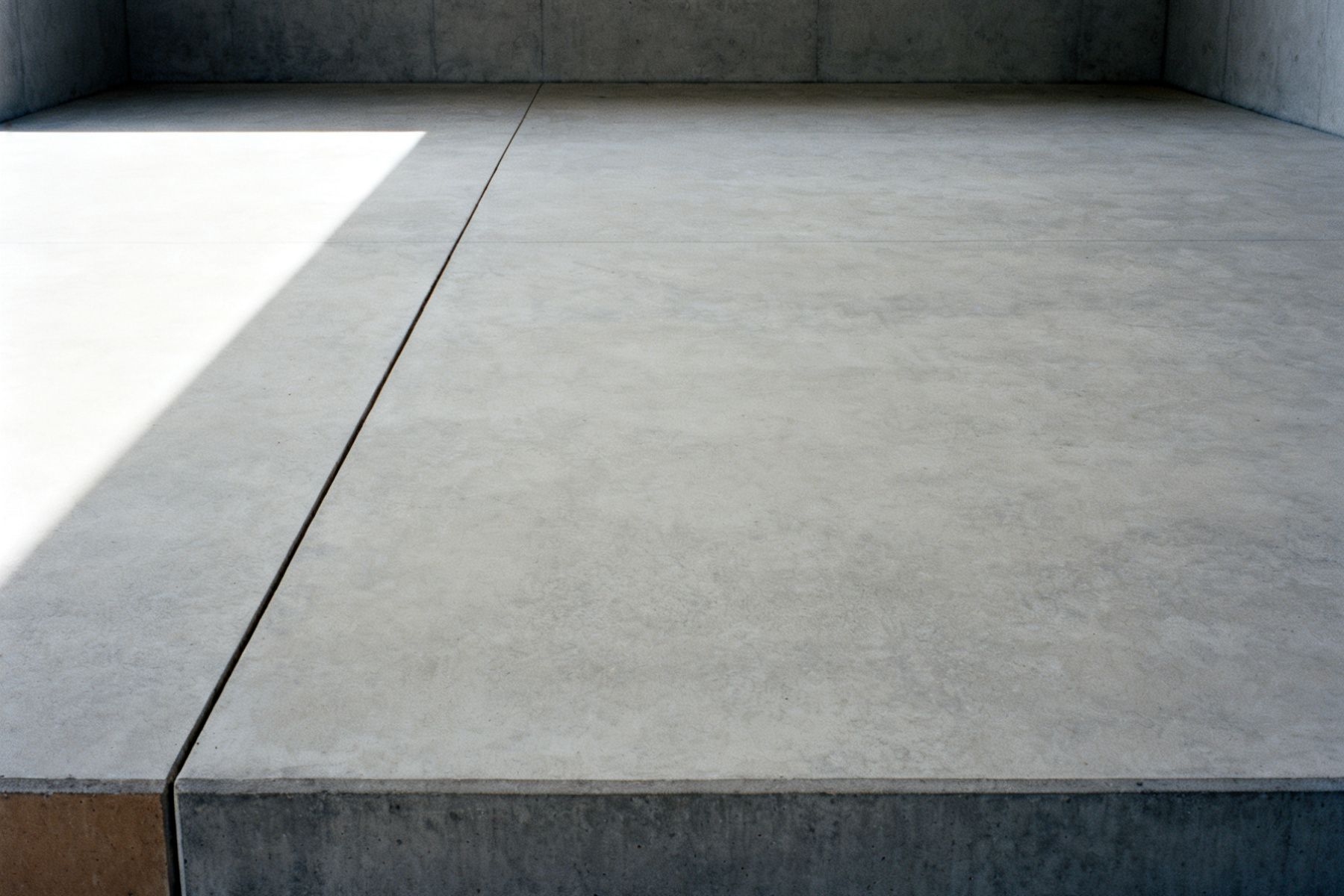 Glatte Betonwand mit einer feinen Fuge, weiches Seitenlicht