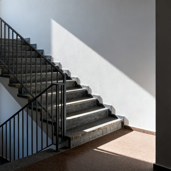 Treppenhaus eines Wohnhauses am frühen Morgen, geschlossene Wohnungstür im Halbdunkel
